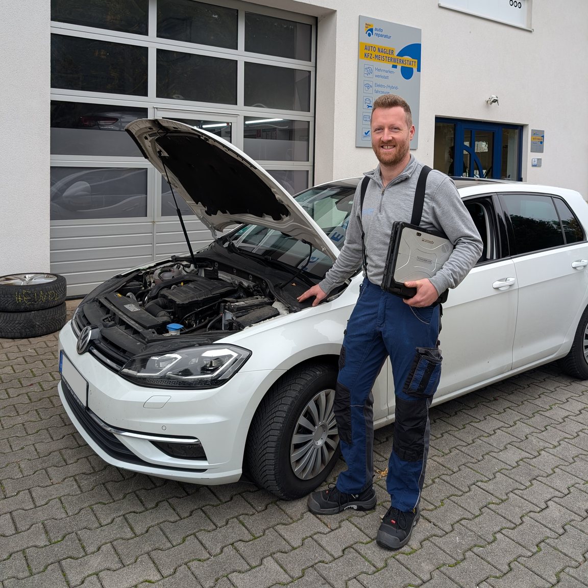 Daniel Nagler mit dem Diagnose-Laptop am Fahrzeug vor der Werkstatt